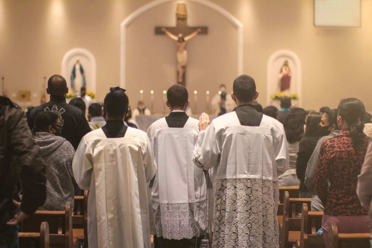 Pessoas dentro da igreja lendo uma mensagem para o dia do catequista 2024