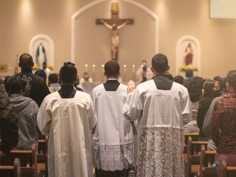 Pessoas dentro da igreja lendo uma mensagem para o dia do catequista 2024