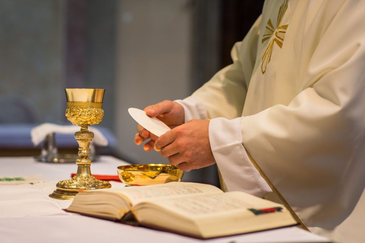 Mensagem dia Padre 2025. A imagem mostra um sacerdote consagrando a eucaristia durante a missa.
